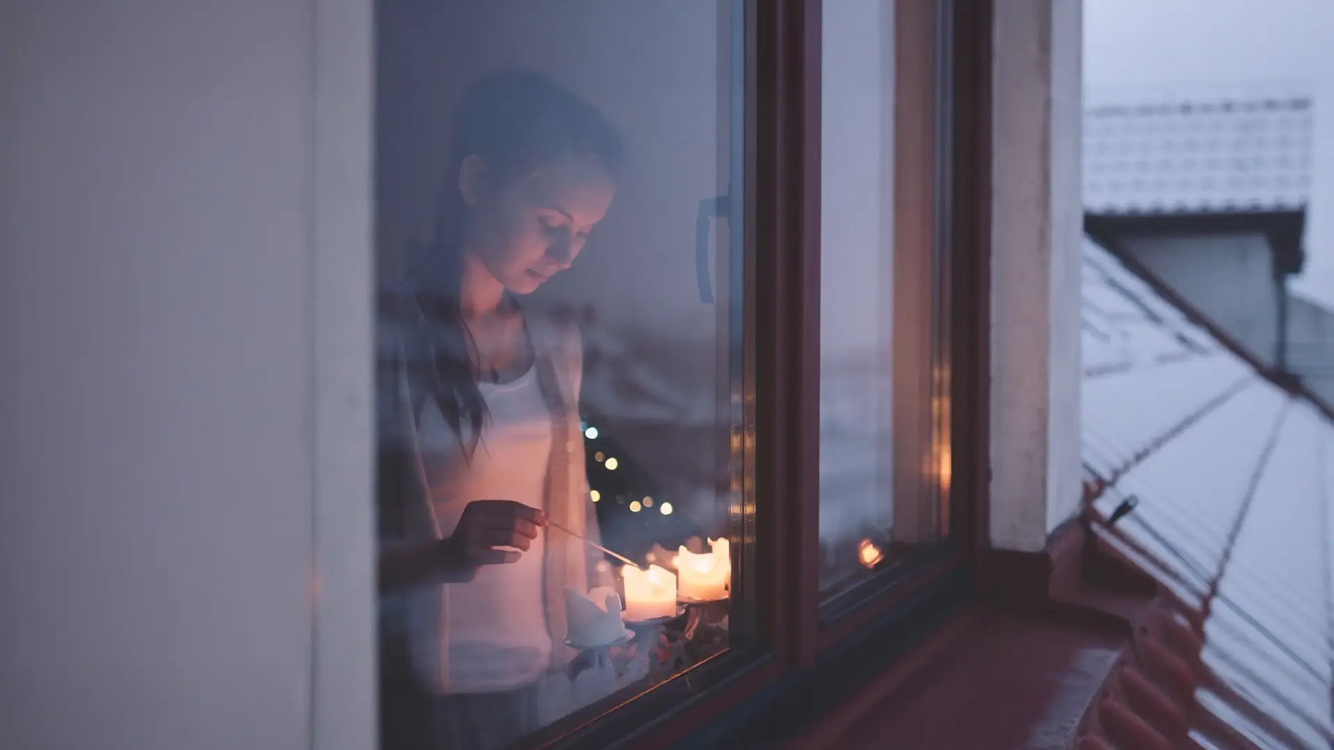 Woman standing in a window lighting candles